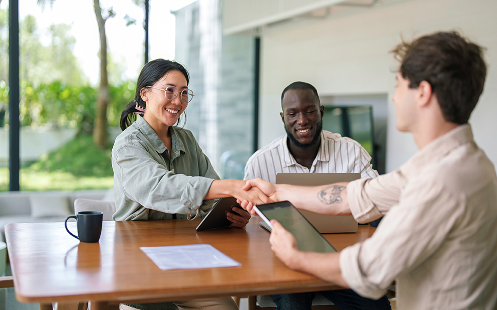 Couple shaking hands and speaking with advisor inside their home