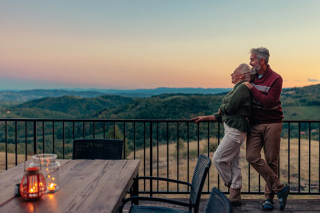 Older couple embracing each other while over looking sunset on home patio
