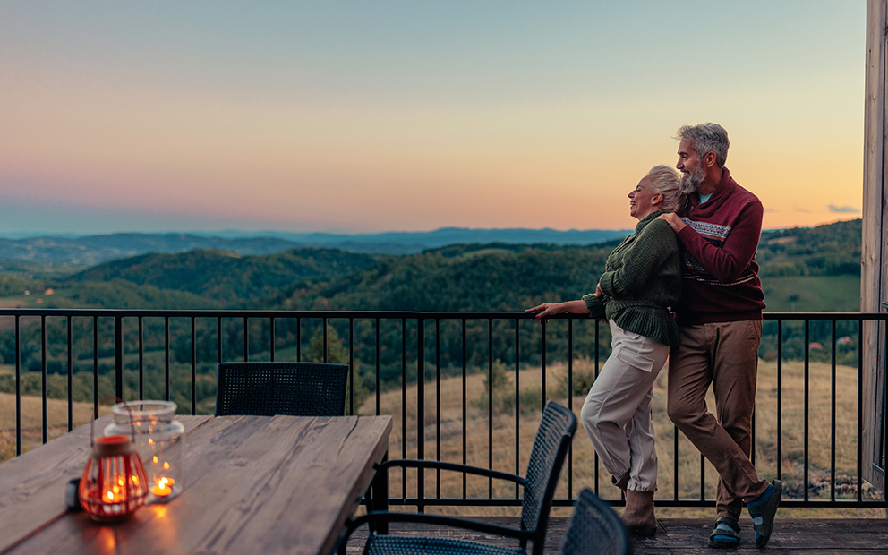 Older couple embracing each other while over looking sunset on home patio
