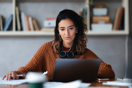 Young woman sitting a desk while looking at laptop screen