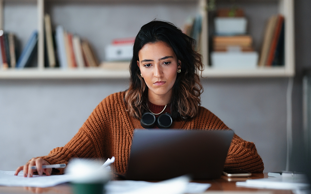 Young woman sitting a desk while looking at laptop screen