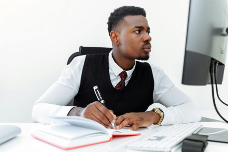Man researching on computer and taking notes