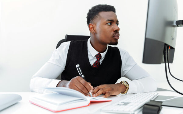 Man researching on computer and taking notes