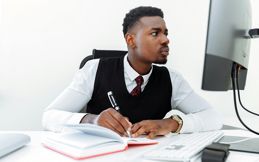 Man researching on computer and taking notes