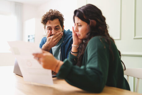 Couple looking shocked while reading mail