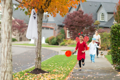 Woman accompanying her two children as they trick or treat