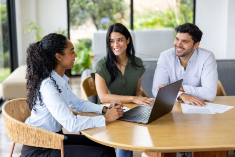 Couple smiling and discussing with agent at home