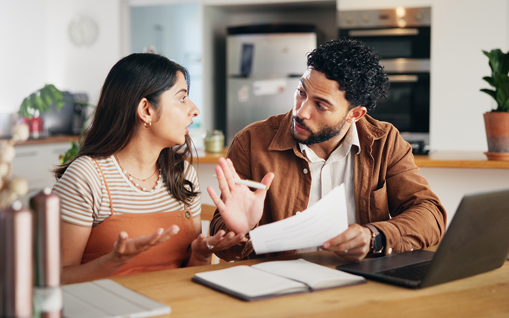 Couple sitting together at home while upset and discussing finances