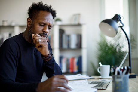 Man looking at documents and taking notes while sitting at home desk