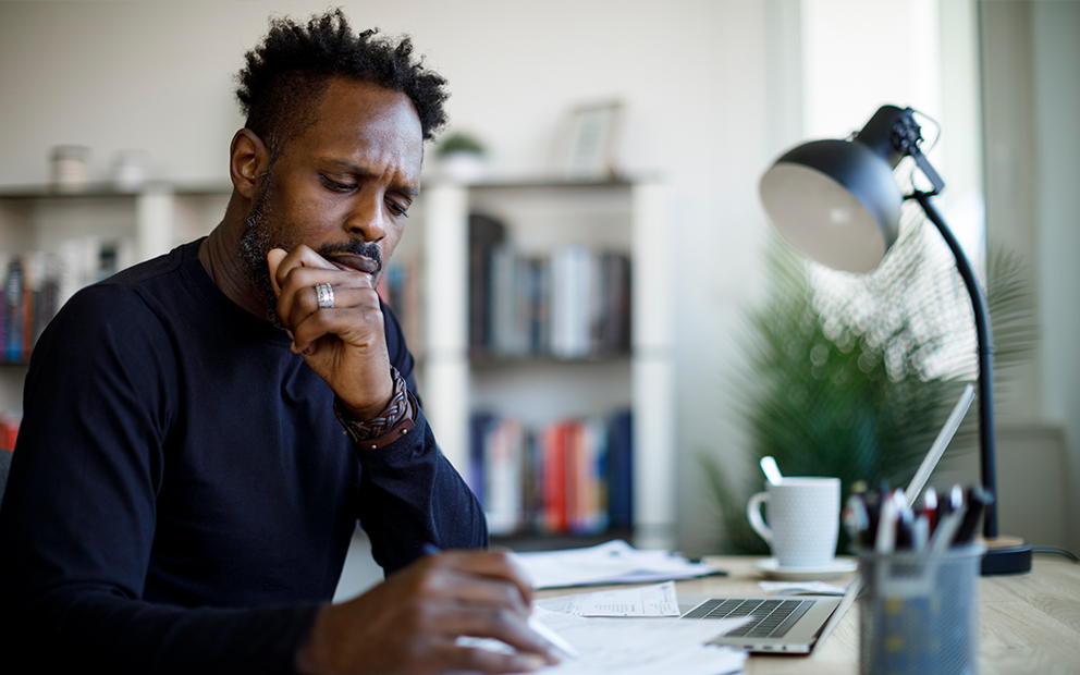 Man looking at documents and taking notes while sitting at home desk