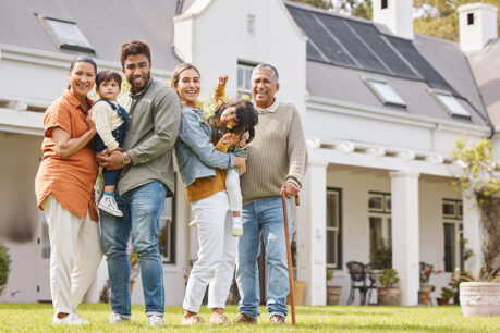 Larger family smiling and hugging outside newly purchased home