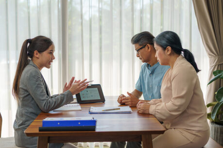 Woman explaining to older couple while sitting with them at home table