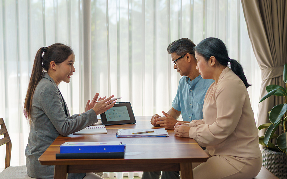 Woman explaining to older couple while sitting with them at home table
