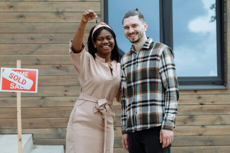 Couple holding up keys to new house on front steps