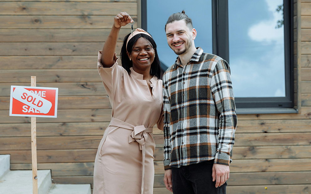 Couple holding up keys to new house on front steps
