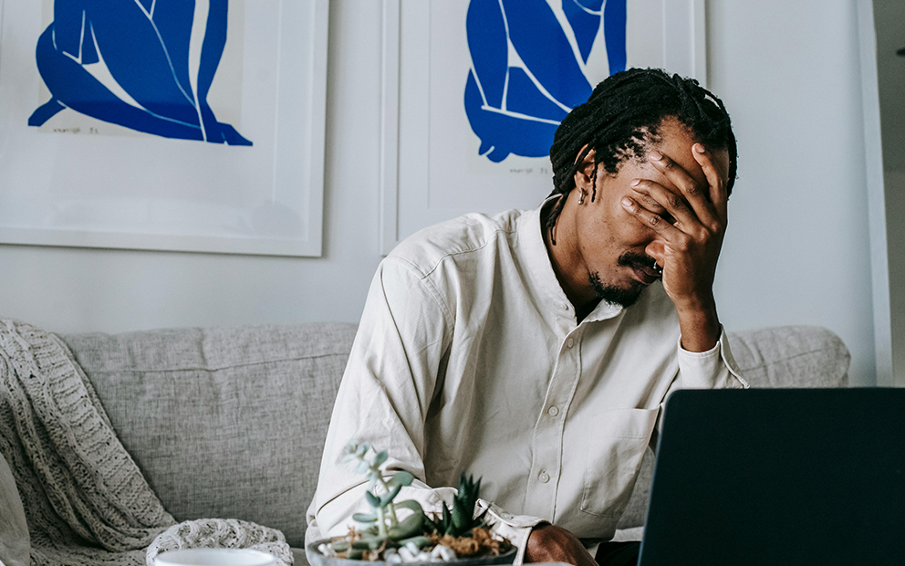 Guy looking stressed while reviewing info on laptop