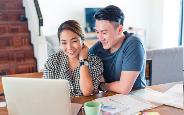 Couple sitting in home together while they look over laptop