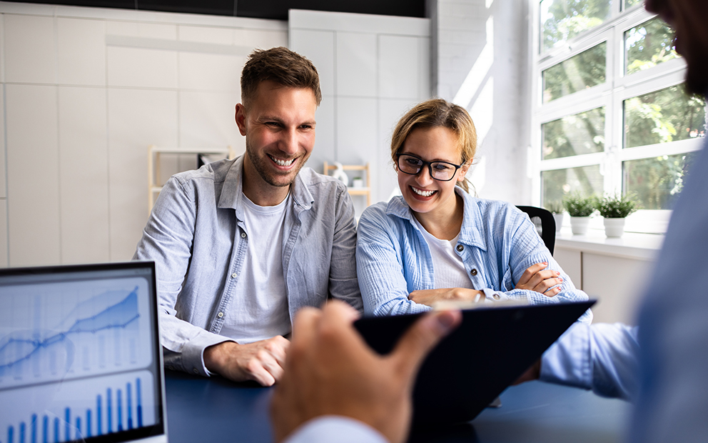 Couple reviewing options on tablet with advisor