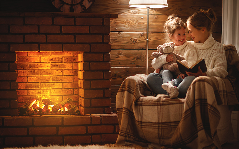 Family spending time together by lit fireplace at home