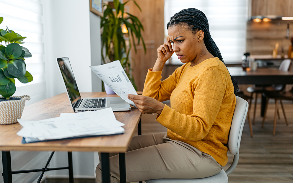 Woman with concerned look on her face while she looks over document at home
