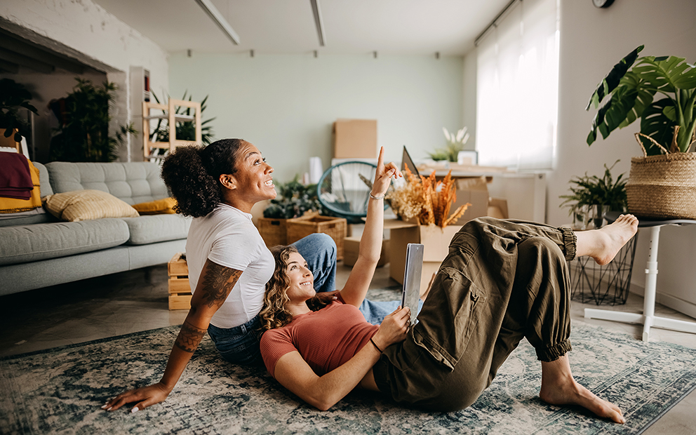 Couple smiling and sitting together on floor of living room