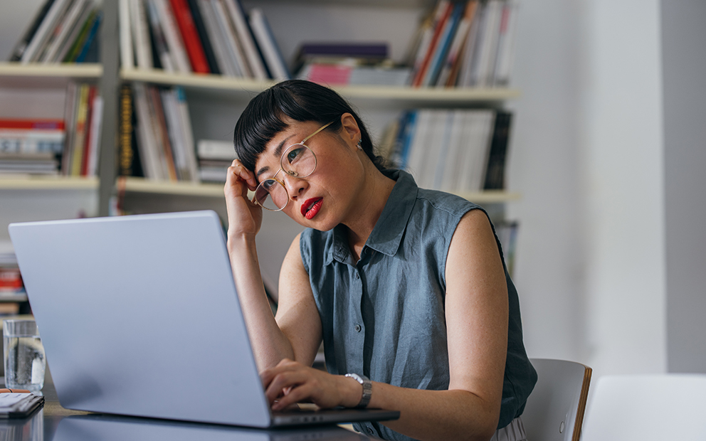 Woman looking over information on laptop while sitting in home office