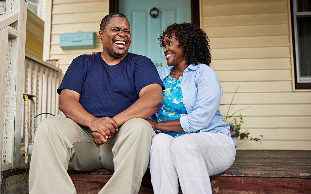 Happy middle aged couple sitting together on home porch steps