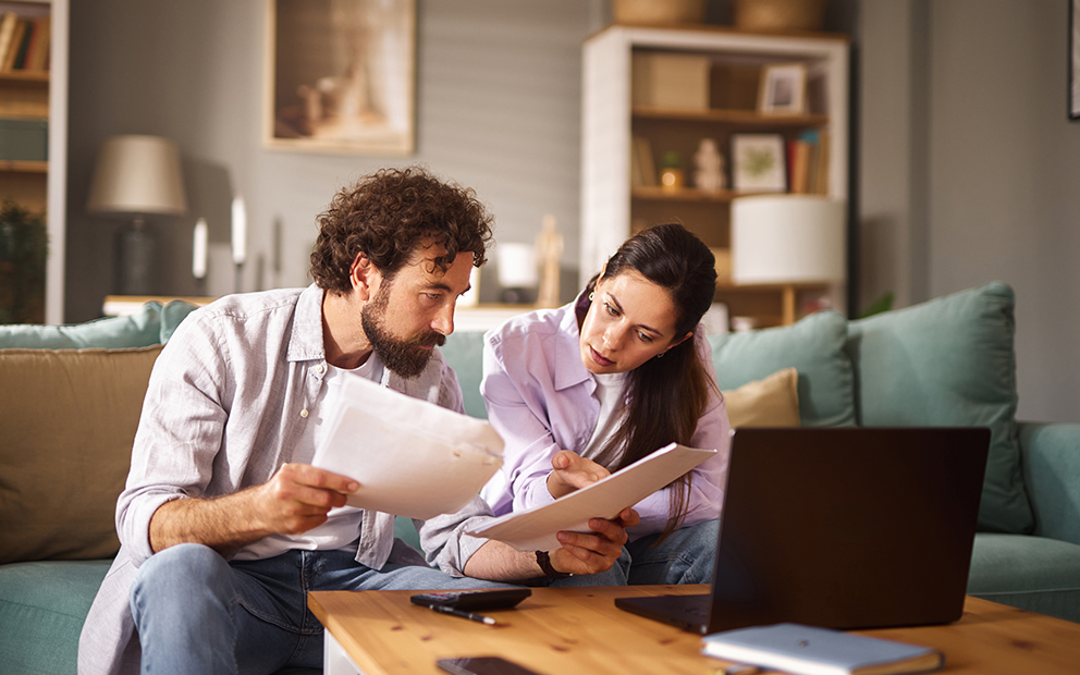 Couple sitting on couch together while discussing documents