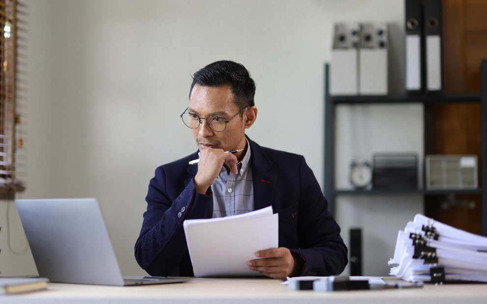 Man sternly reviewing documents on home computer