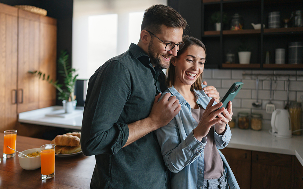 Man and woman couple smiling while looking at cell phone together