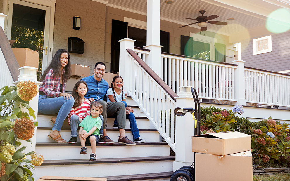 Family sitting on porch outside of new house