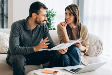 Couple discussing while sitting on couch at home