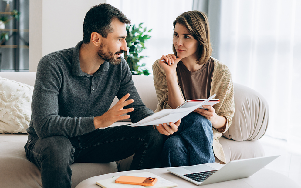 Couple discussing while sitting on couch at home