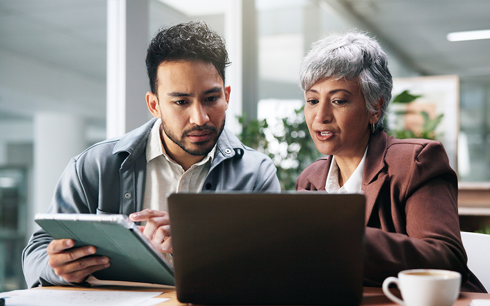 Man speaking with advisor in office while reviewing computer