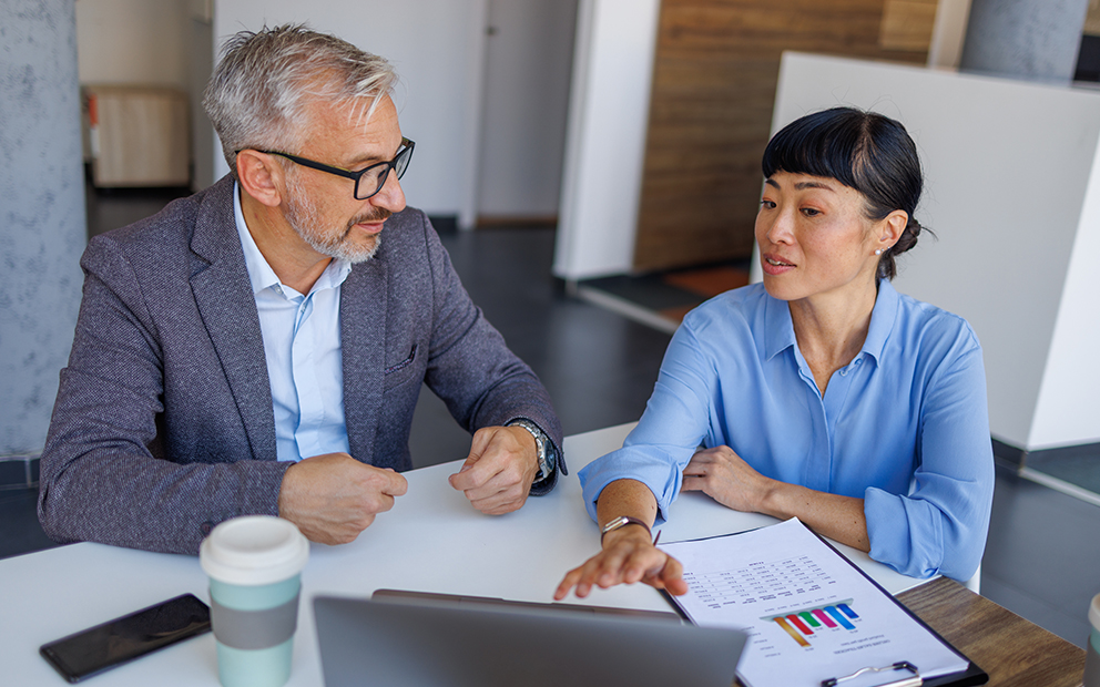 Advisor speaking with older client about documents at table