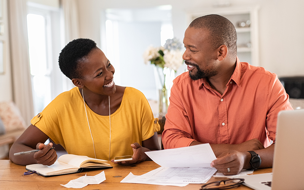 Middle-aged couple smiling while reviewing and discussing finances