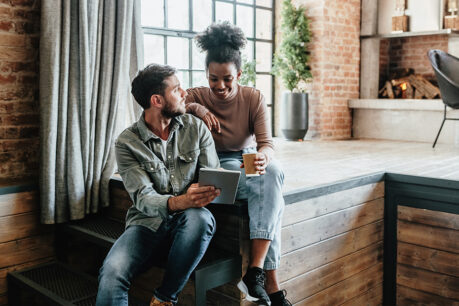Young couple smiling and discussing while looking at tablet screen together