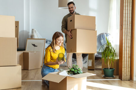 Happy mand and woman couple packing up belongings in home