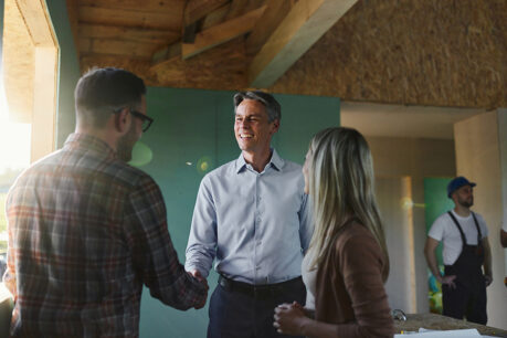 Couple speaking with realtor in home mid-construction