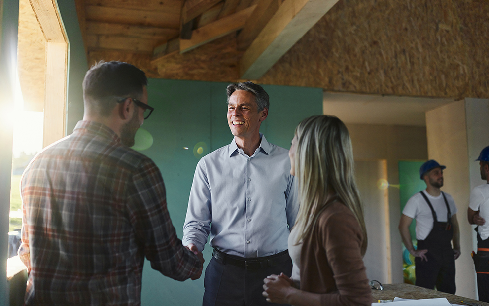 Couple speaking with realtor in home mid-construction