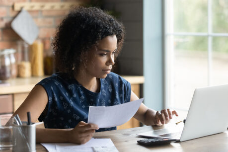 Woman researching info and finances on laptop while sitting at home
