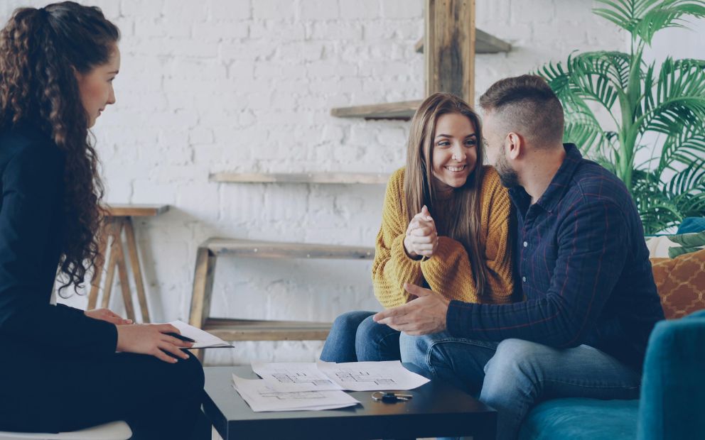 Couple smiling while speaking with a banker about buying a house as-is