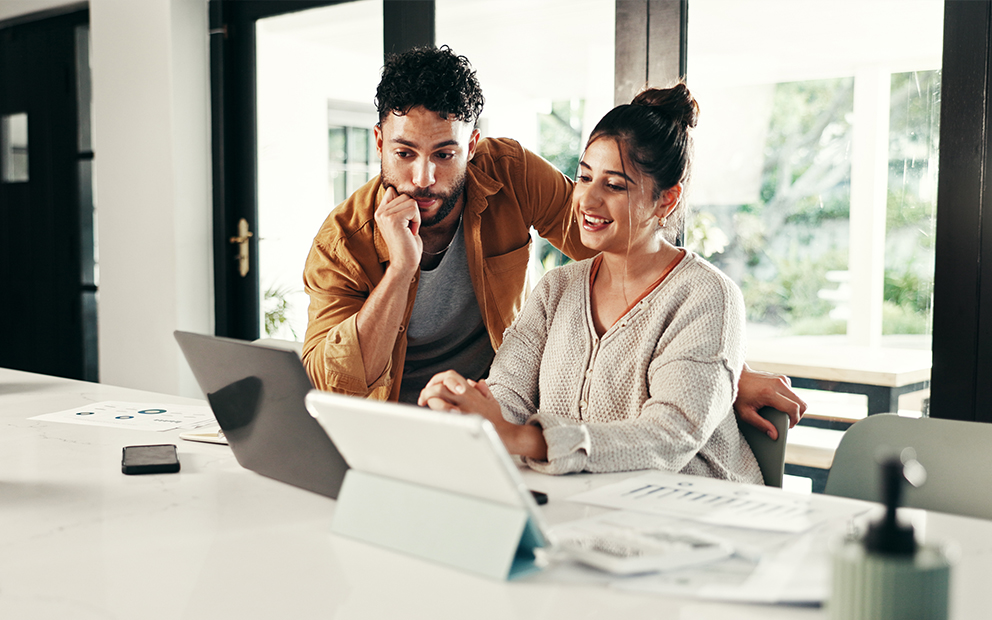 Couple reviewing documents on laptop while at home together