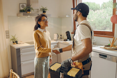 Woman shaking hands with handyman inside home