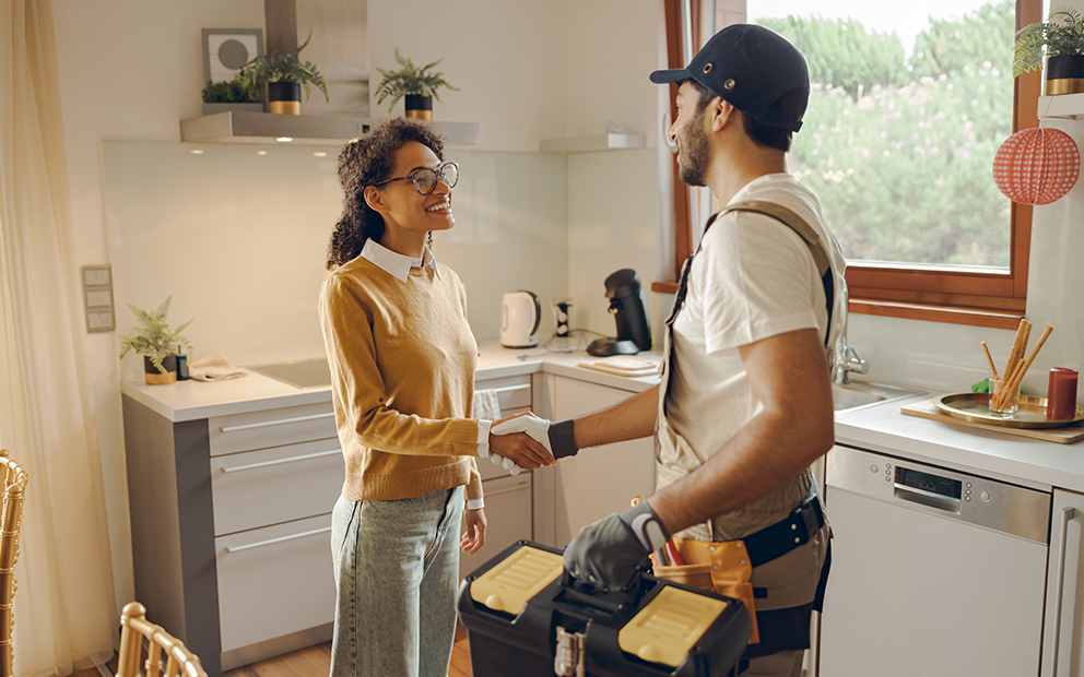 Woman shaking hands with handyman inside home
