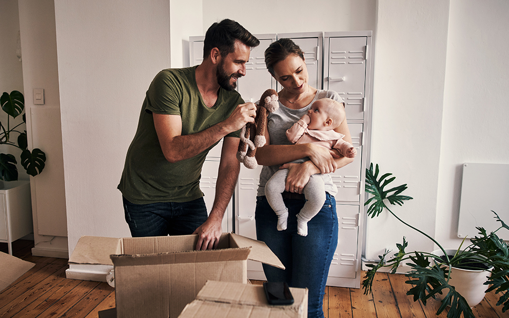 Young couple showing their newborn baby their new home