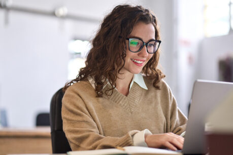 Women smiling while researching on laptop