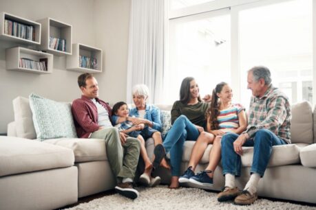 Multi-generational family sitting together at home on the couch