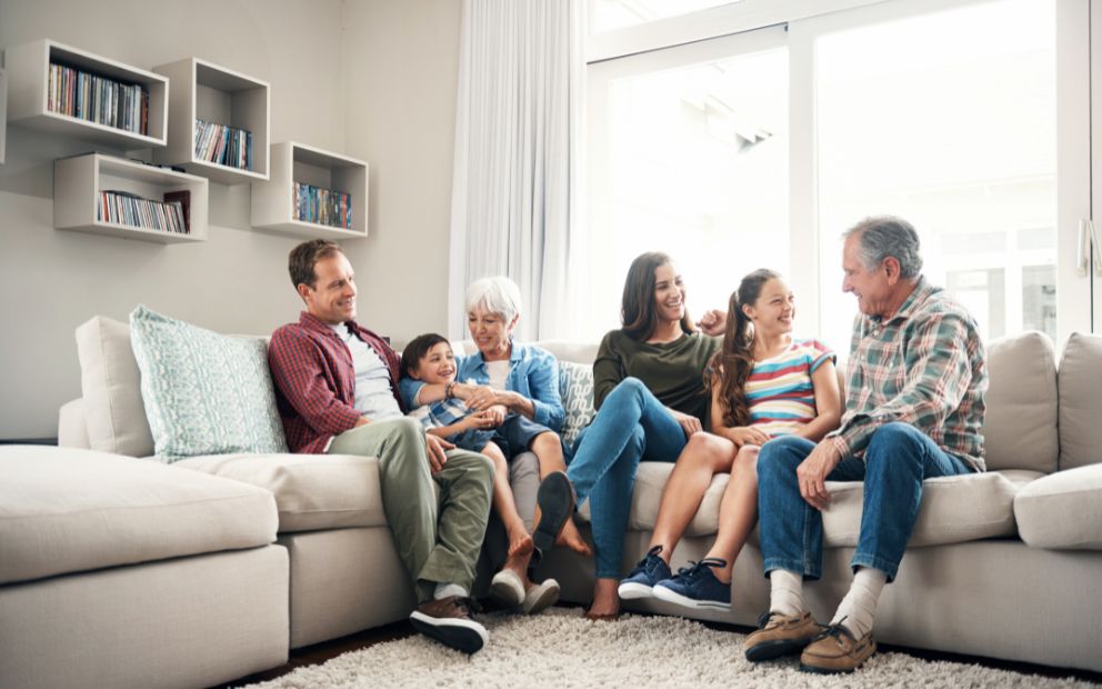 Multi-generational family sitting together at home on the couch