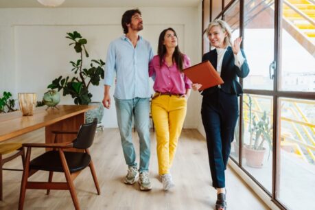 Man and woman couple touring home with realtor and discussing multiple offers on a house